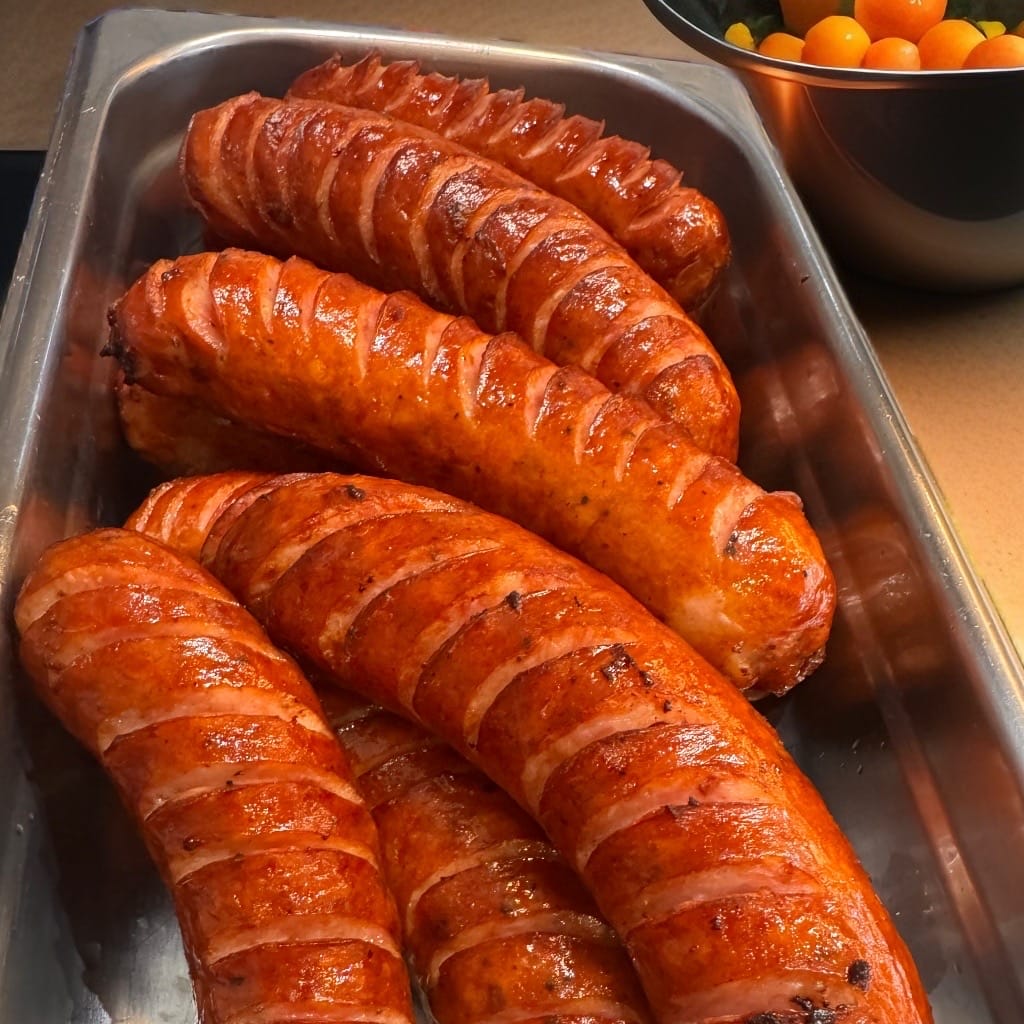 Grilled kielbasa glistening in a hot bar tray